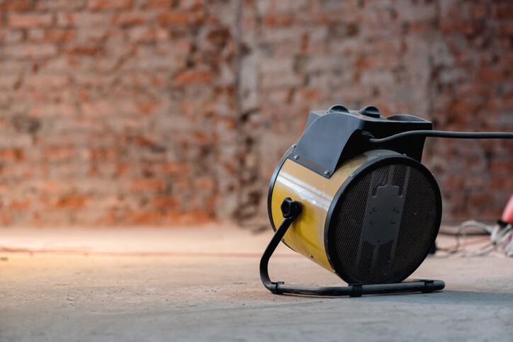 yellow blow heater in front of internal brick wall