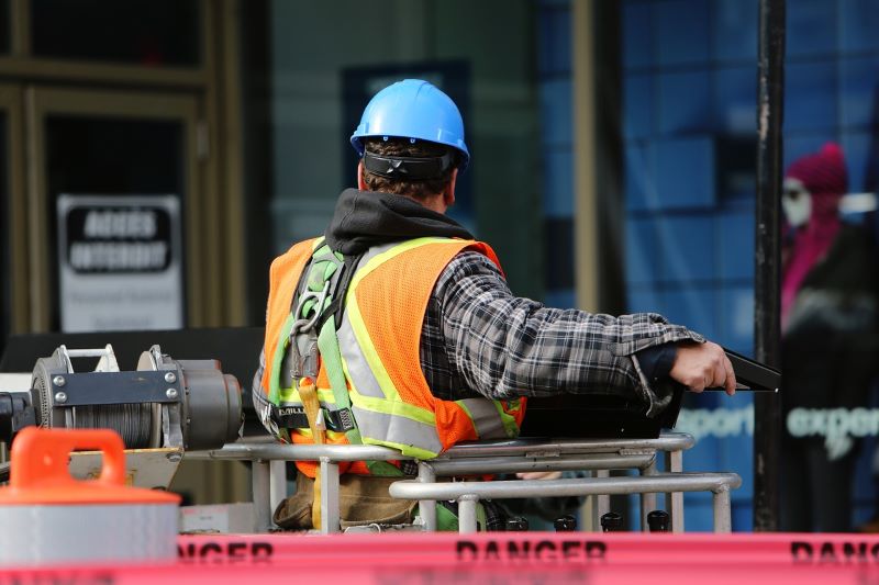 construction worker in orange safety vest seen from behind