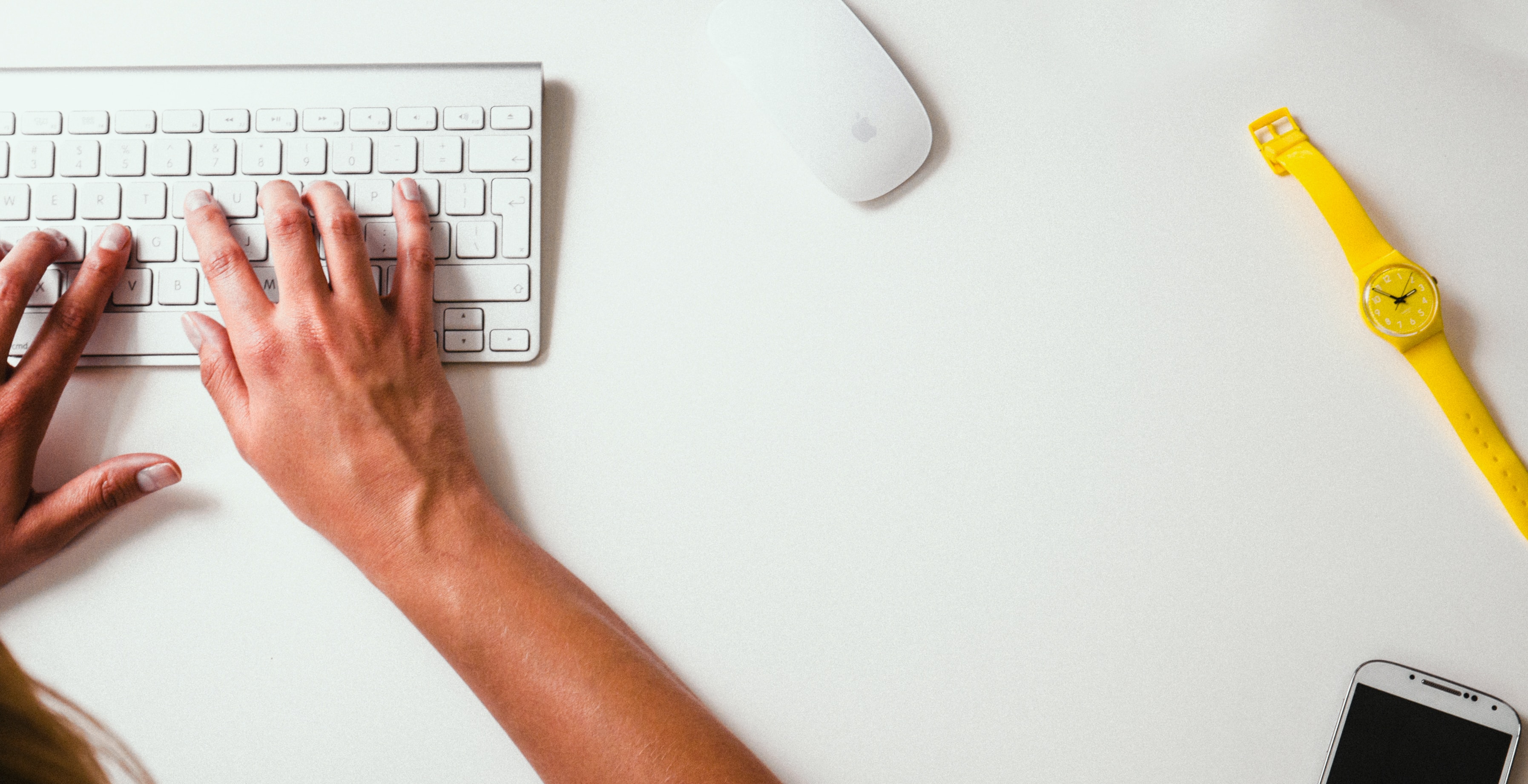aerial shot of handstyping on white keyboard
