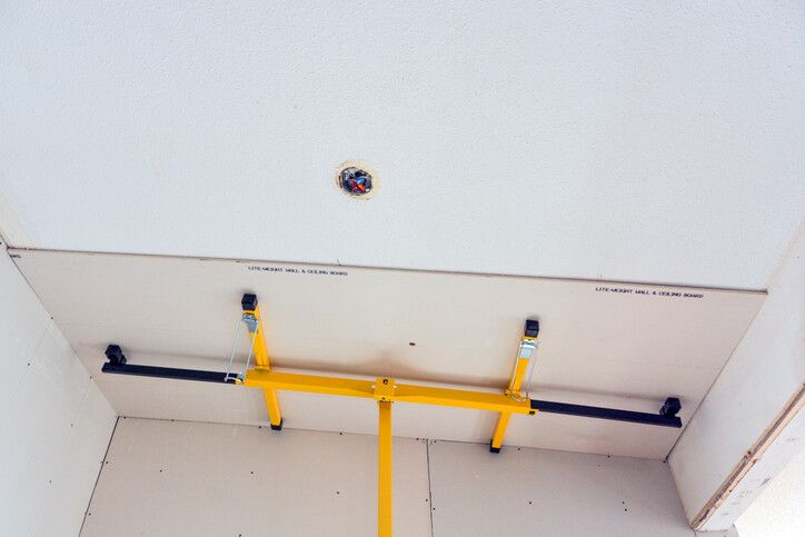 drywall being lifted up to ceiling with plasterboard lifter 