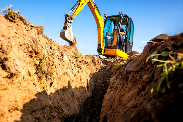 ground  view from trech being dug out by yellow excavator