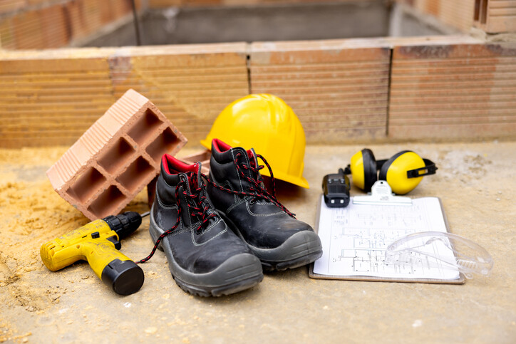 image of safety boots, yellow hard hat, ear protectors, drill