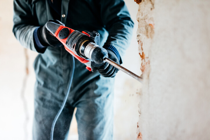 man using breaker on concrete wall