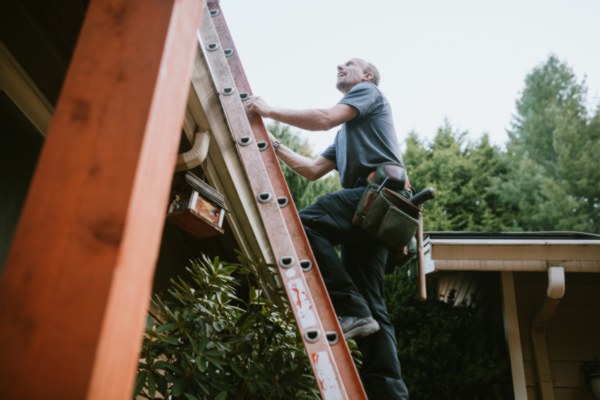 man-with-toolbag-climbing-ladder-to-roof