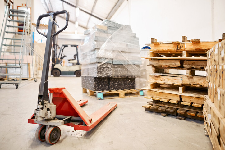 pallet-truck-on-warehouse-floor-near-stack-of-pallets