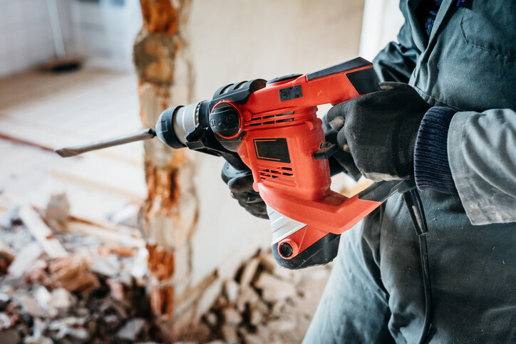 Red breaker held in front of demolished wall