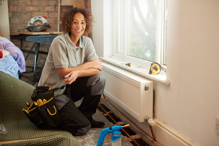 Smiling woman kneeling on floor by radiator