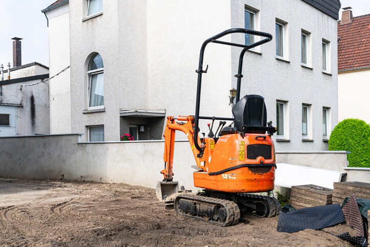 Unmanned ornge mini excavator at residential construction site.
