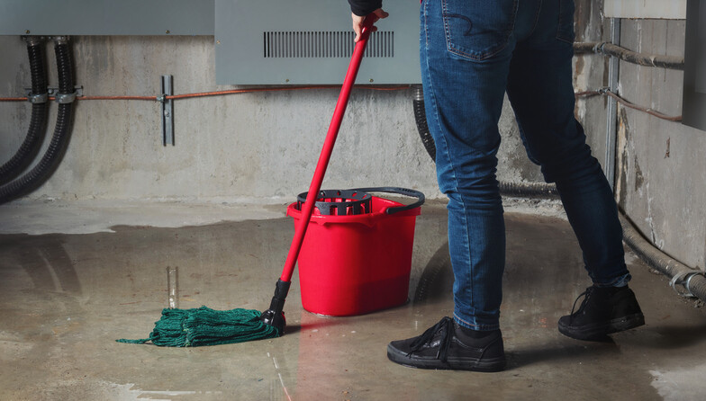 Waist-down-view-of-man-mopping-flooded-basement-floor