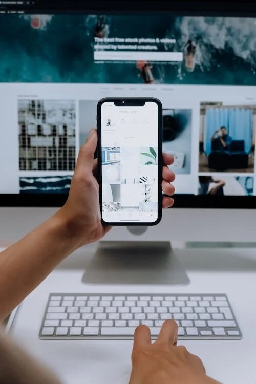 mobile phone held up in front of computer monitor