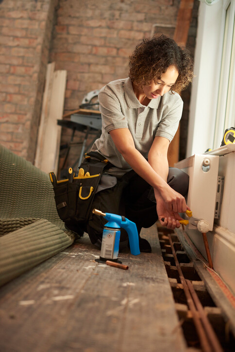 woman adjusting radiator valve with pliers