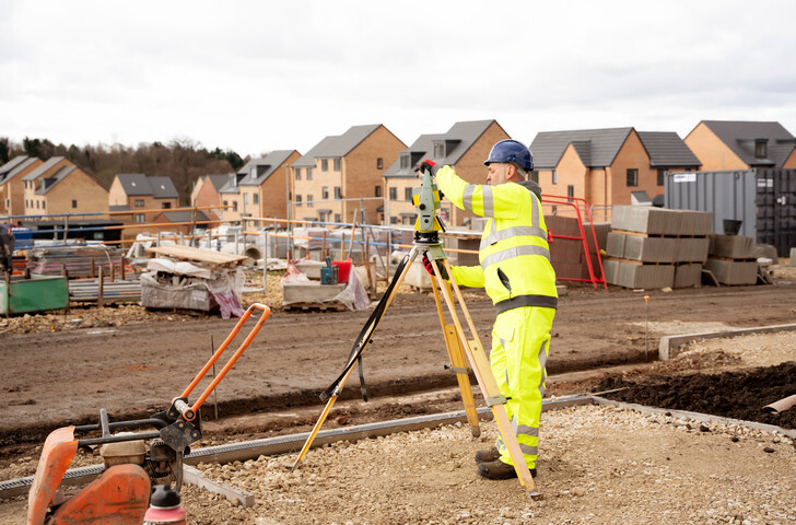worker setting up laser level on residential construction project