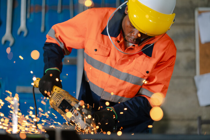 worker wearing helmet and protective shield using angle grinder