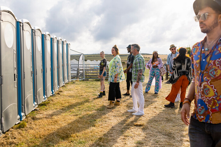 Young people at sumer festival queing at potable toilets